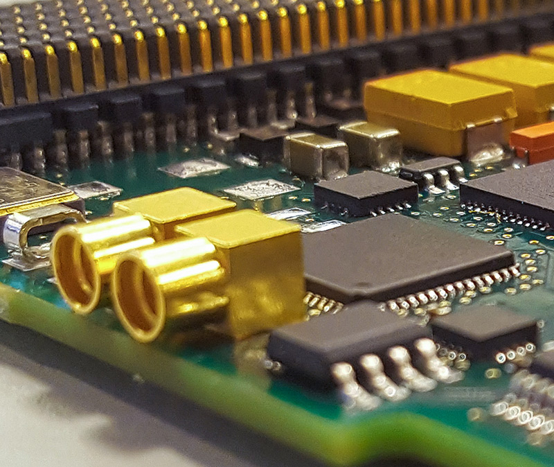 数据采集与控制 - 附有电缆和连接器的电子测试设备特写，控制面板上有各种刻度盘和按钮。背景呈虚化效果。