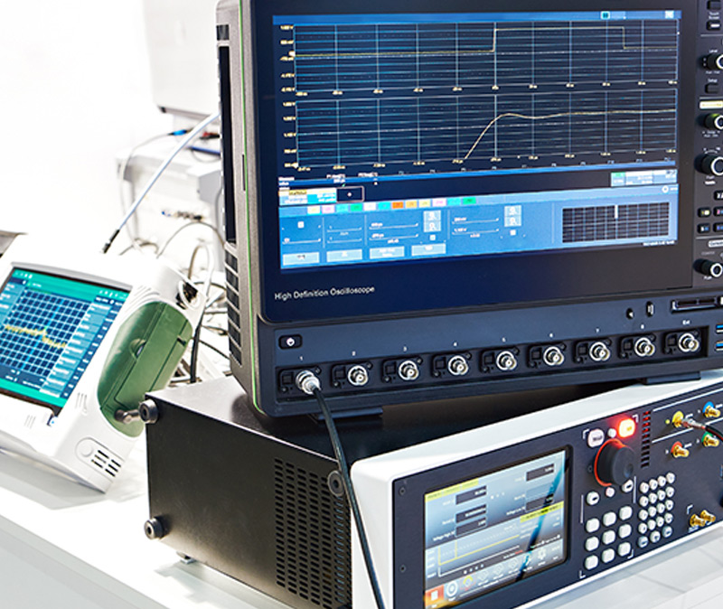 信号和电源发生 - 摆放在桌子上的一套电子测试设备，包括一台示波器和一个带有显示图形和数据的屏幕的控制面板。