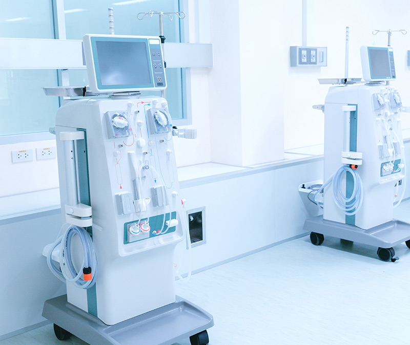 Medical Equipment - Two dialysis machines stand in a clean, modern hospital room with medical equipment attached and monitors on top.